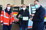 „RescueWave neue DRK-Fahrzeuge – Wölfel, Brechtel, Seefeldt“ (von links) Dr. Matthias Wölfel, Sprecher der Leitenden Notärzte und die Landräte Dr. Fritz Brechtel (GER) und Dietmar Seefeldt (SÜW). Sie zeigen die Anhängersender, die verletzte Personen umgehängt bekommen und entscheidende Informationen direkt an die Notärzte und Rettungskräfte schicken. Foto: Kreisverwaltung Germersheim/KV GER/mda 