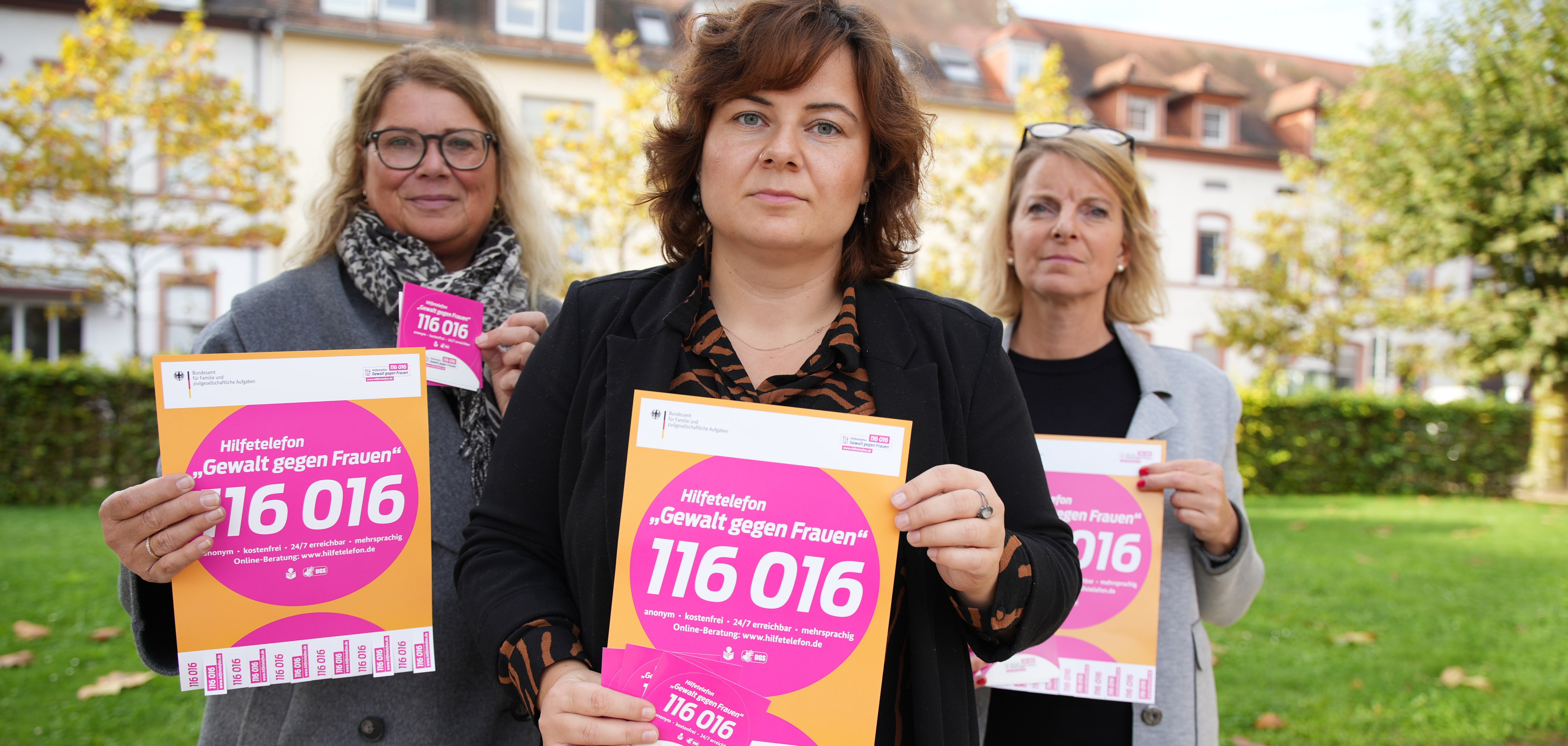 Bildunterschrift: Die Gleichstellungsbeauftragten Julier, Trog und Stähle (von links nach rechts) weisen auf die Nummer des Hilfetelefons hin.


