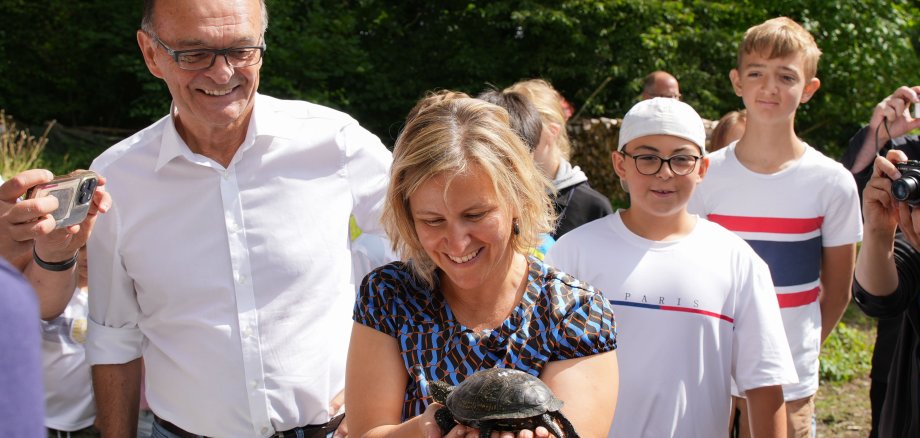 Ministerin Katrin Eder und Landrat Dr. Fritz Brechtel setzen eine Sumpfschildkröte aus. Zur Aussiedlungsaktion waren auch zahlreiche Interessierte aus dem Ort gekommen, darunter eine Seniorengruppe und eine zweite Klasse der Grundschule Neuburg.