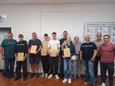 Sieben Anglerinnen und Angler zeigen beim Gruppenbild mit Prüfern ihre Zertifikate über eine erfolgreiche abgelegte Fischerprüfung.
