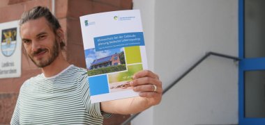 Fabian Braun, zuständig für die Themen Dorferneuerung, Geoinformation und Räumliche Planung bei der Kreisverwaltung Germersheim, mit der druckfrischen Ausgabe einer neuartigen Broschüre „Klimaschutz bei der Gebäudeplanung bedeutet Lebensqualität“.