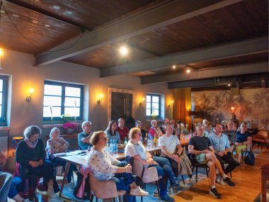 Das Foto zeigt ein Gruppe an Frauen und Männern in einem rustikalen Raum mit viel Holzelementen. Es handelt sich hierbei um ein Vermietertreffen in der Holzmühle in Westheim.