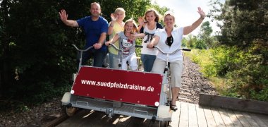 Eine Draisinenfahrt ist Spaß für Groß und Klein! das foto zeigt eine familie bei der Draisinenfahrt.