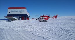 foto einer wetterstation im eis, daneben stehend ein helikopter.