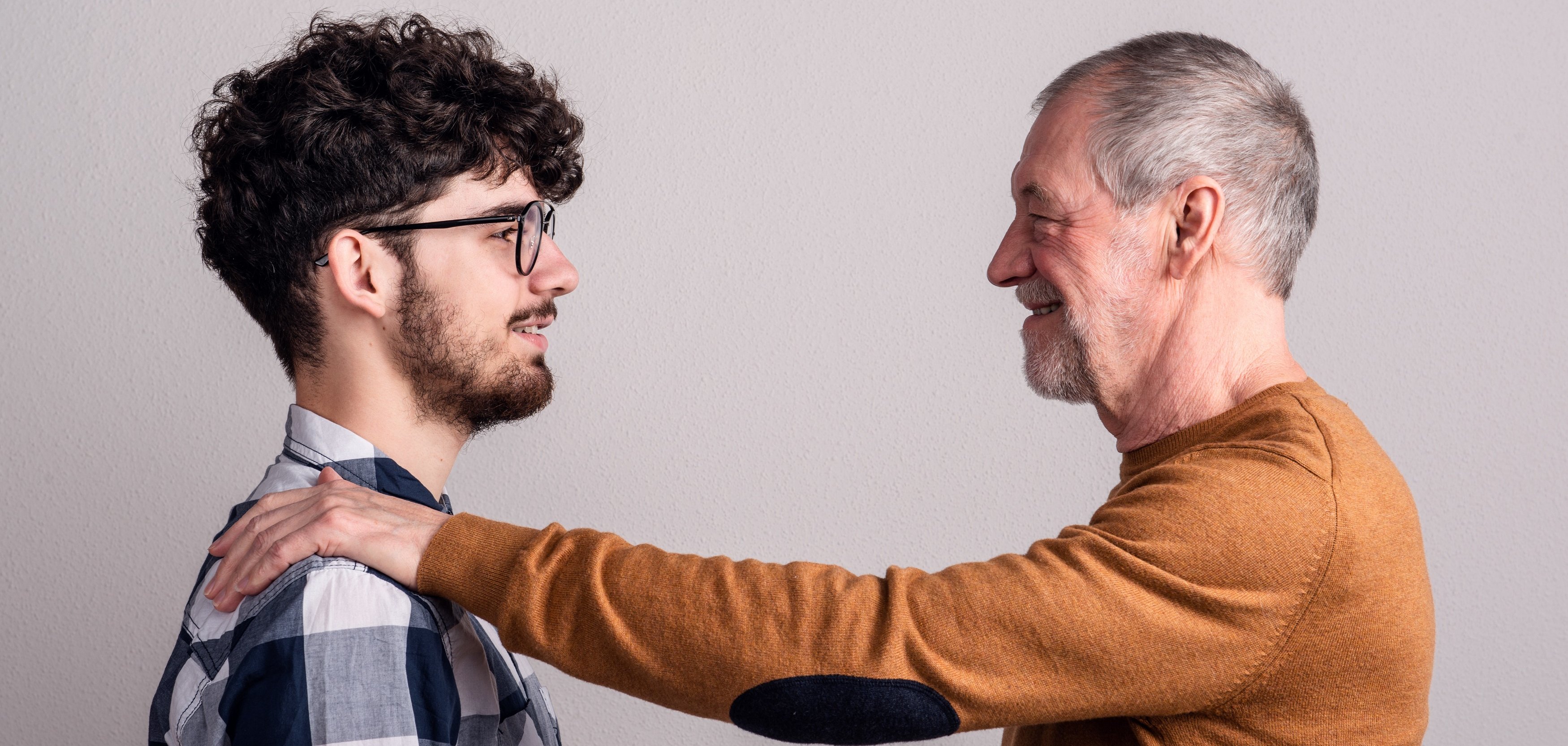 ein älterer mann klopft einem jüngeren auf die schulter