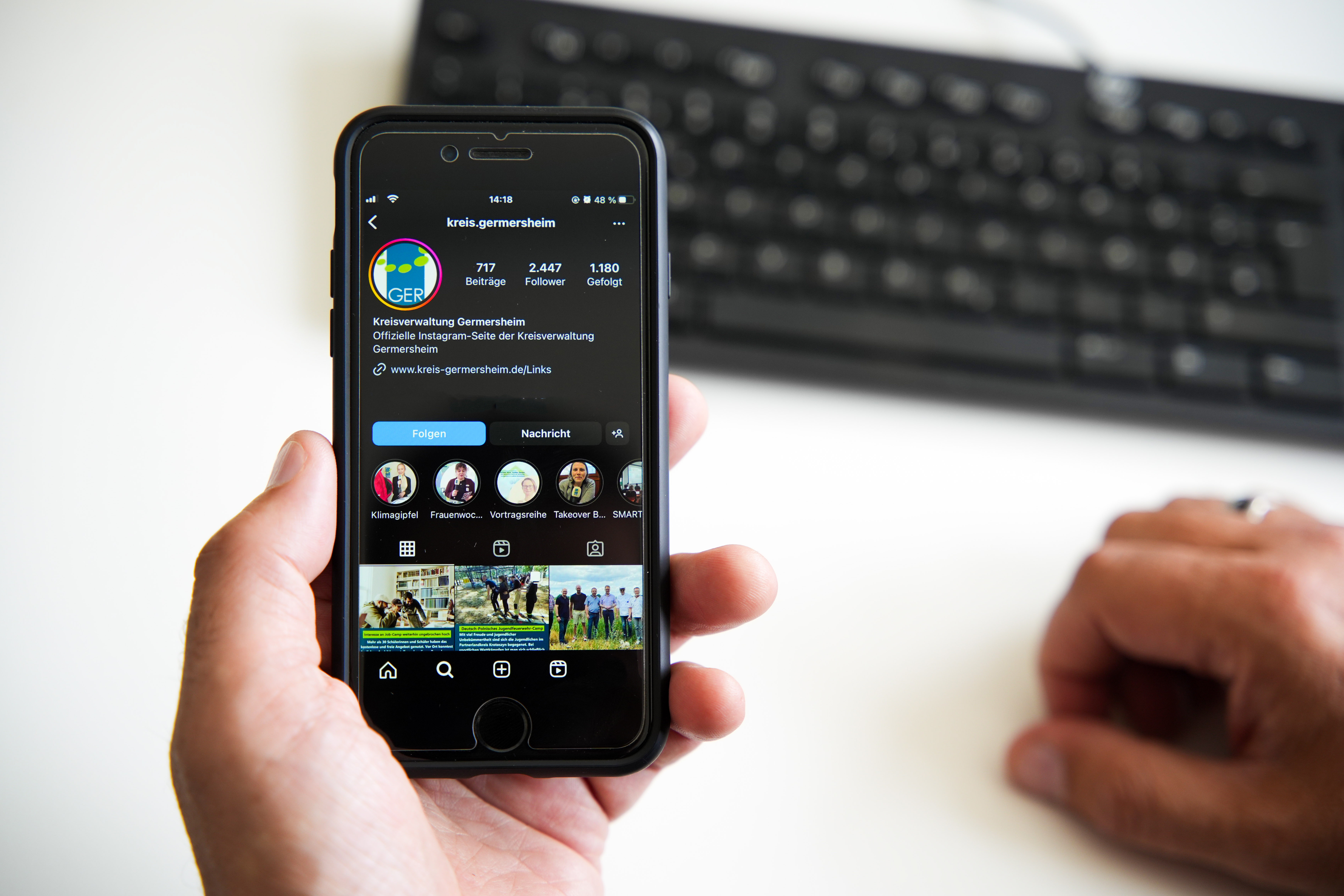 hände halten ein phone vor dem hintergrund einer pc-tastaur.